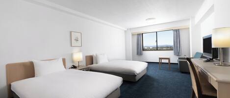 A hotel room with two beds, a desk, a chair, a TV, and a window with a view.