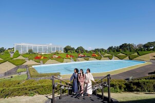 Una amplia estructura de invernadero de cristal con una piscina y jardines ajardinados al fondo.