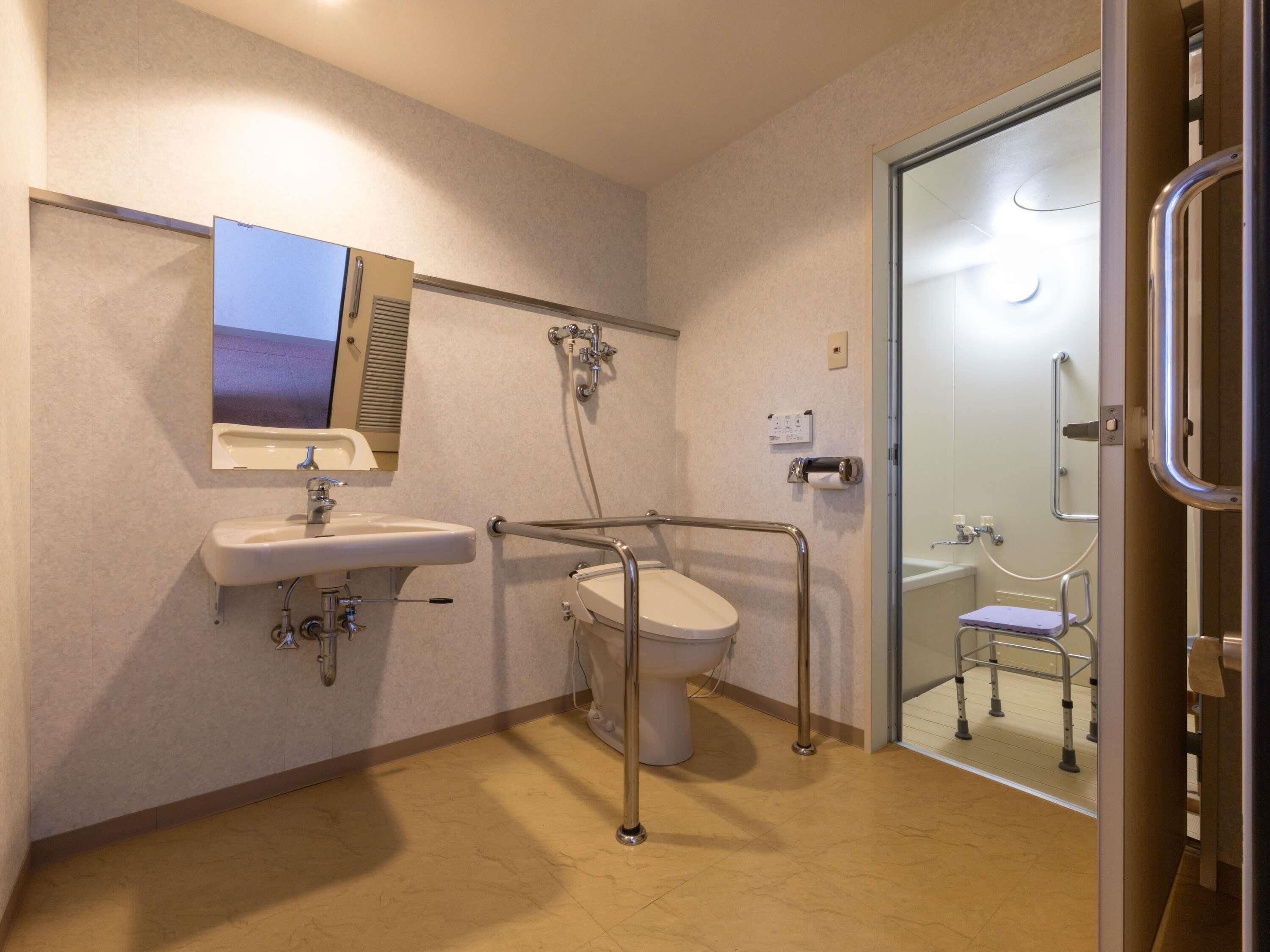 A bathroom with a sink, toilet, and shower area, including grab bars and a wheelchair-accessible shower.