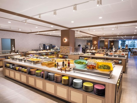 A buffet with various food items and a seating area with tables and chairs.. Mercure Toyama Tonami Resort & Spa