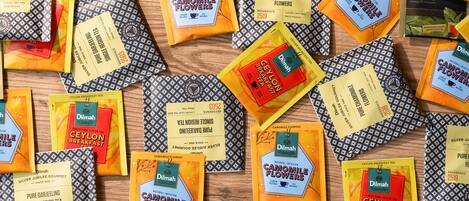 A variety of tea packages and leaf tea bags arranged on a wooden surface.