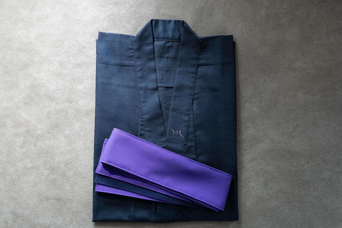 Une chemise bleu foncé, pliée, ornée d’un petit logo brodé sur la partie gauche de la poitrine.