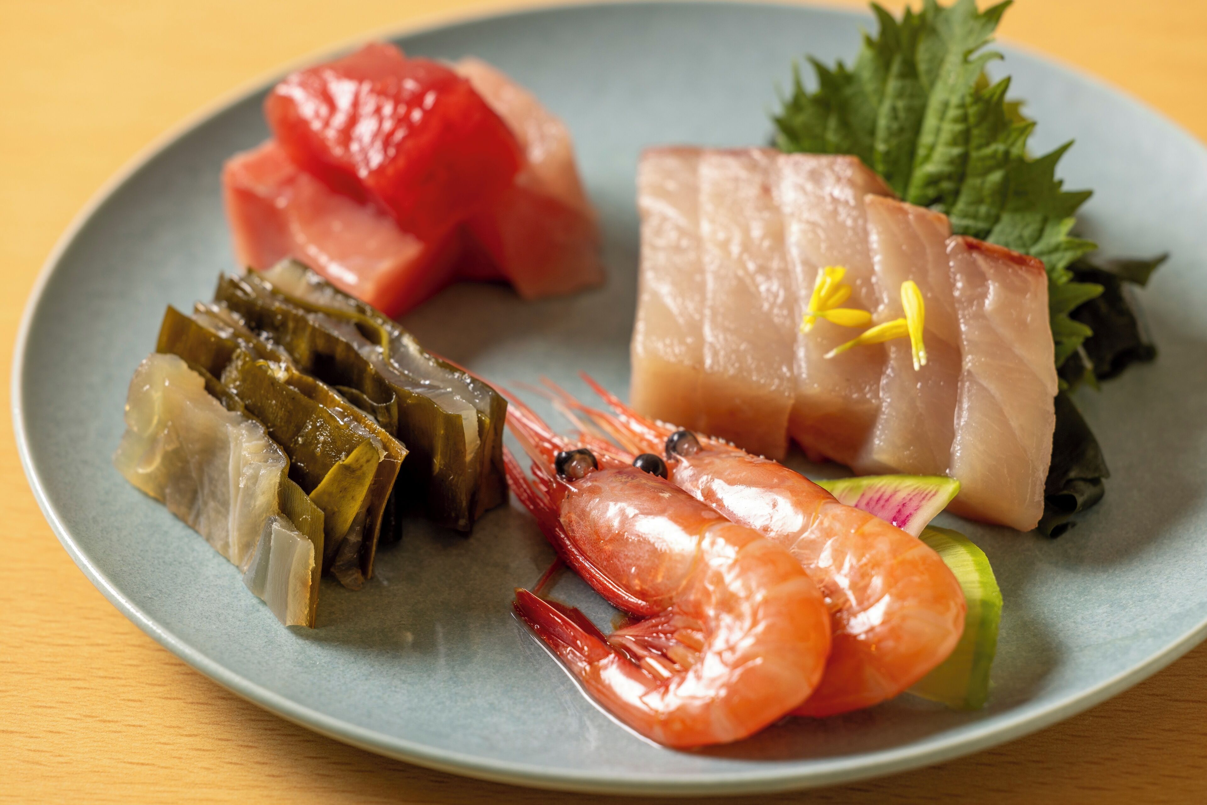 A plate with various seafood items including shrimp, fish, and seaweed.