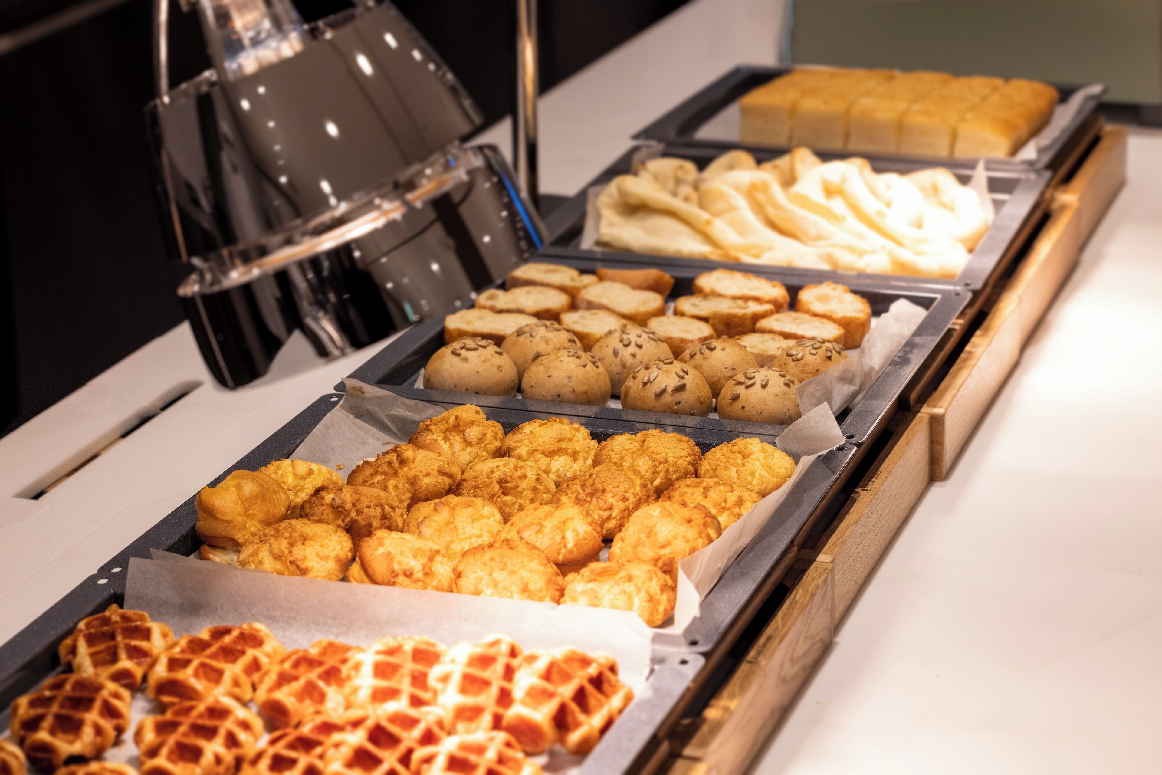 A buffet with various food items including waffles, bread, and fried items.