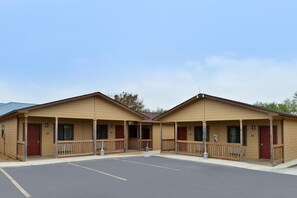 A row of two-story motel buildings with a central parking lot. - The Texas Lodge (Gonzales)