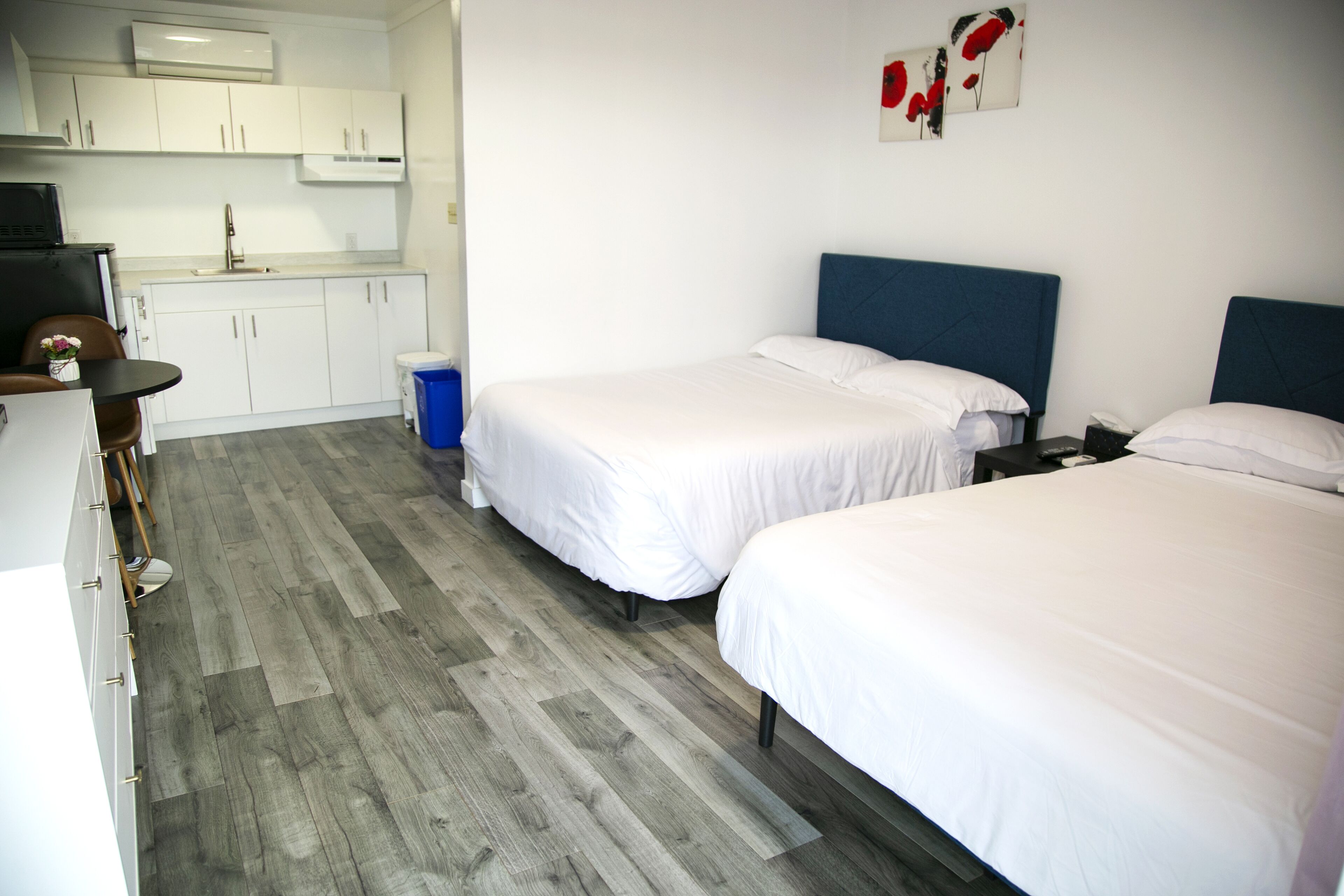 Una habitación de hotel con dos camas individuales, una kitchenette pequeña y un comedor.