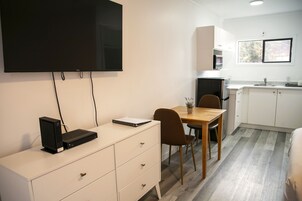 Una cocina moderna con armarios blancos, una mesa de comedor de madera y un televisor de pantalla plana montado en la pared.