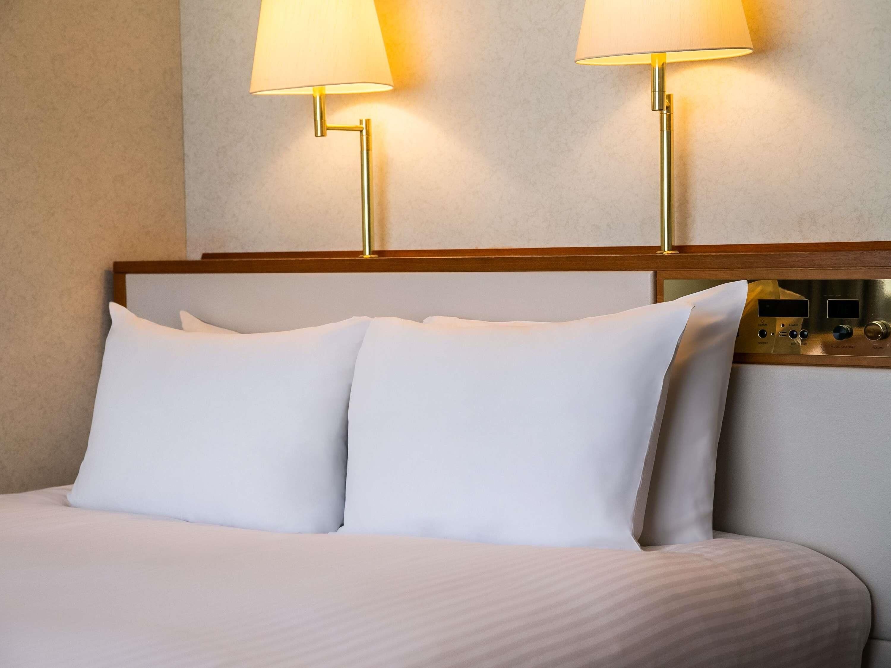 Ein Hotelzimmer mit einem Bett, zwei Nachttischlampen und einer Bedienfeld an der Wand.