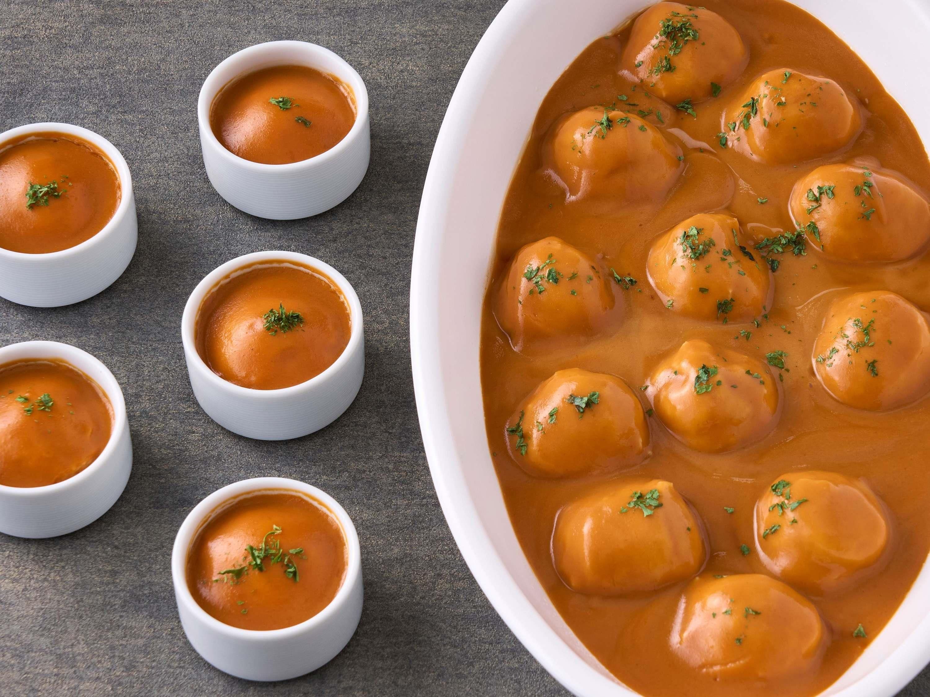 A bowl of soup with dumplings garnished with herbs.