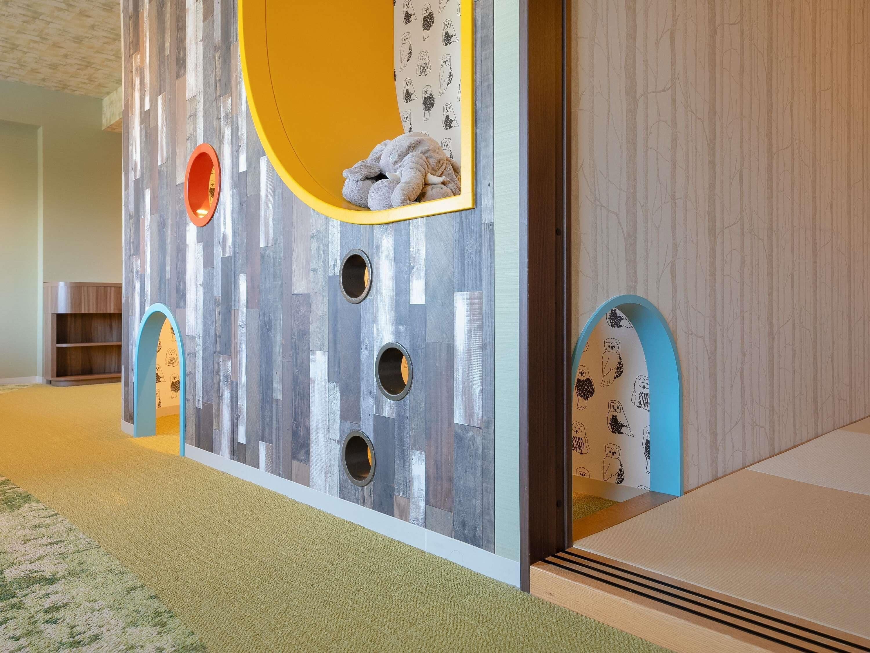 A children's play area with a slide, a soft play structure, and a small seating area.