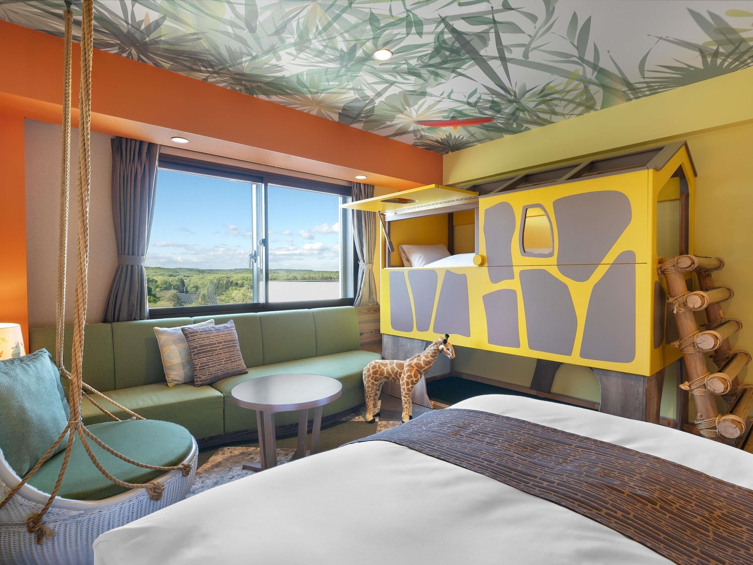 A room with a bunk bed, a sofa, a hanging chair, and a giraffe toy.
