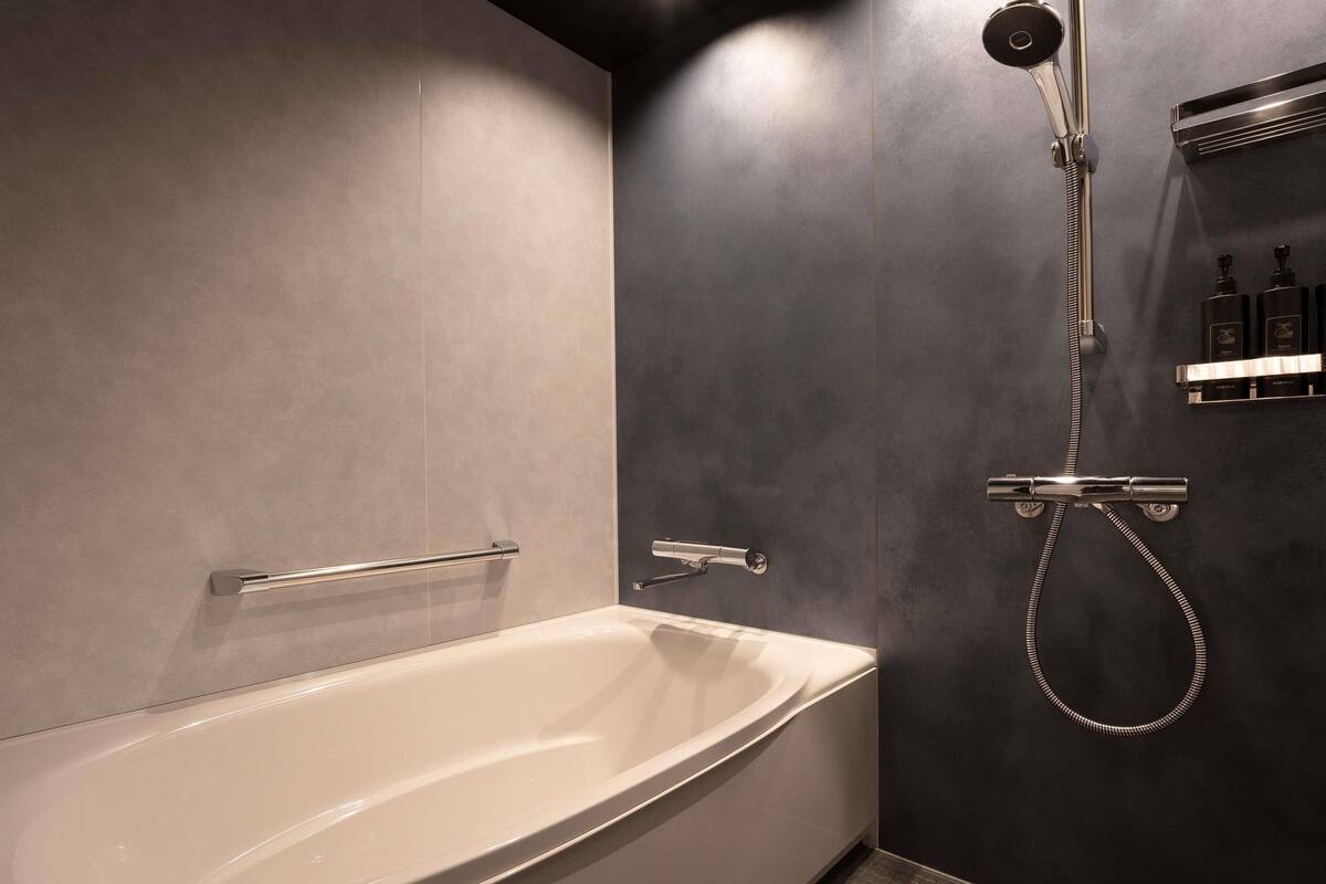 Un baño moderno con una bañera independiente, un cabezal de ducha manual y un grifo empotrado.