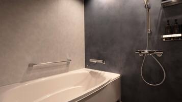 Un baño moderno con una bañera independiente, un cabezal de ducha manual y un grifo empotrado.