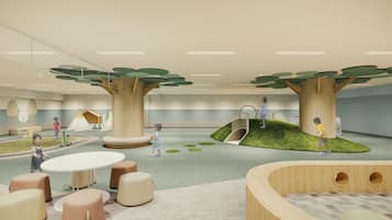 Children can play and climb on the central structure, surrounded by cushioned seating and modern tables.