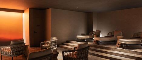 Un moderno spa con sillones de mimbre, una camilla de masaje y una escalera que conduce a una zona privada.