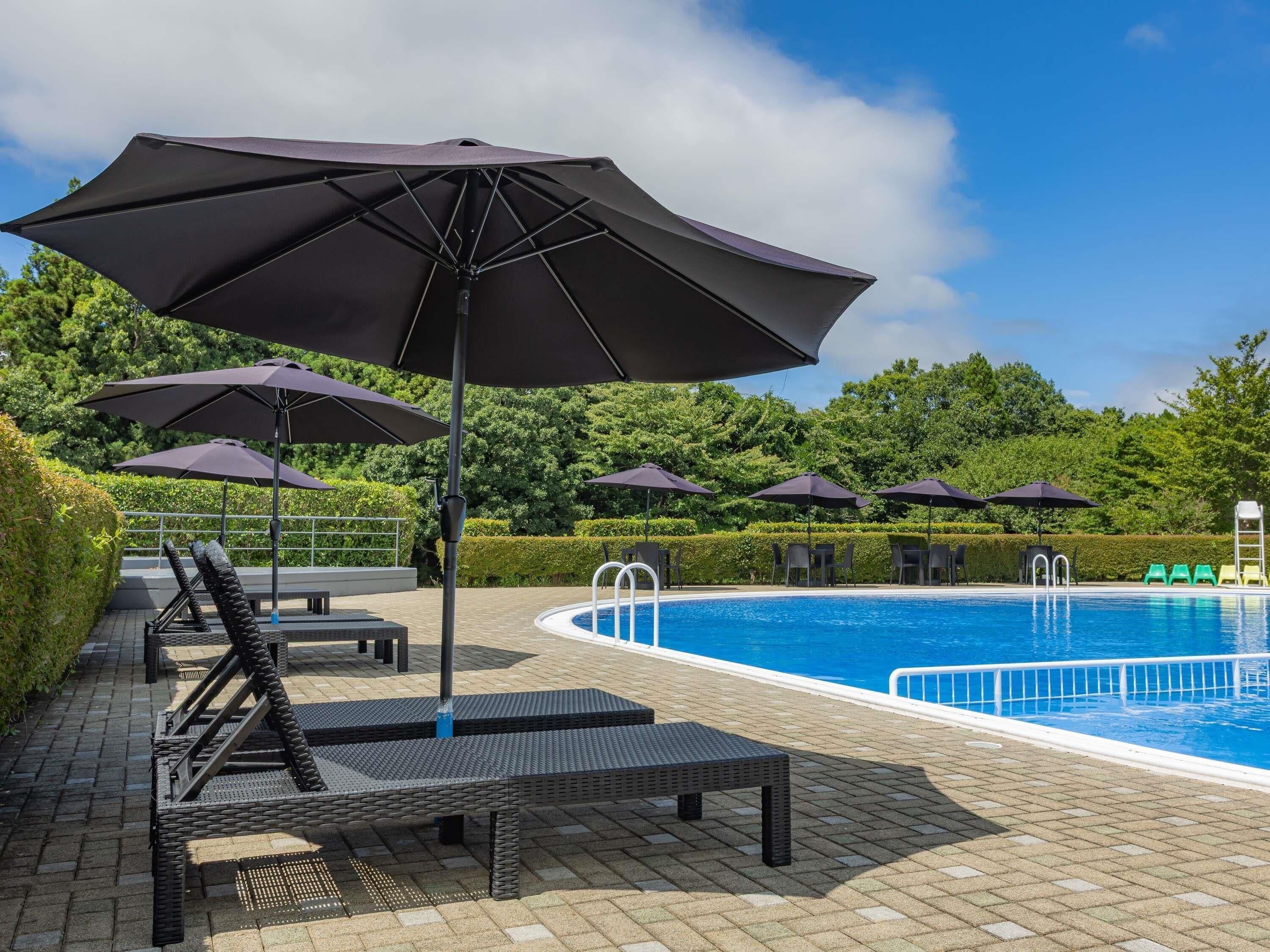 Ein Poolbereich mit Liegestühlen, Sonnenschirmen und einem Schwimmbecken.