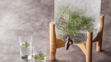 A large ice dispenser with a tap, two glasses, and a wooden stand.