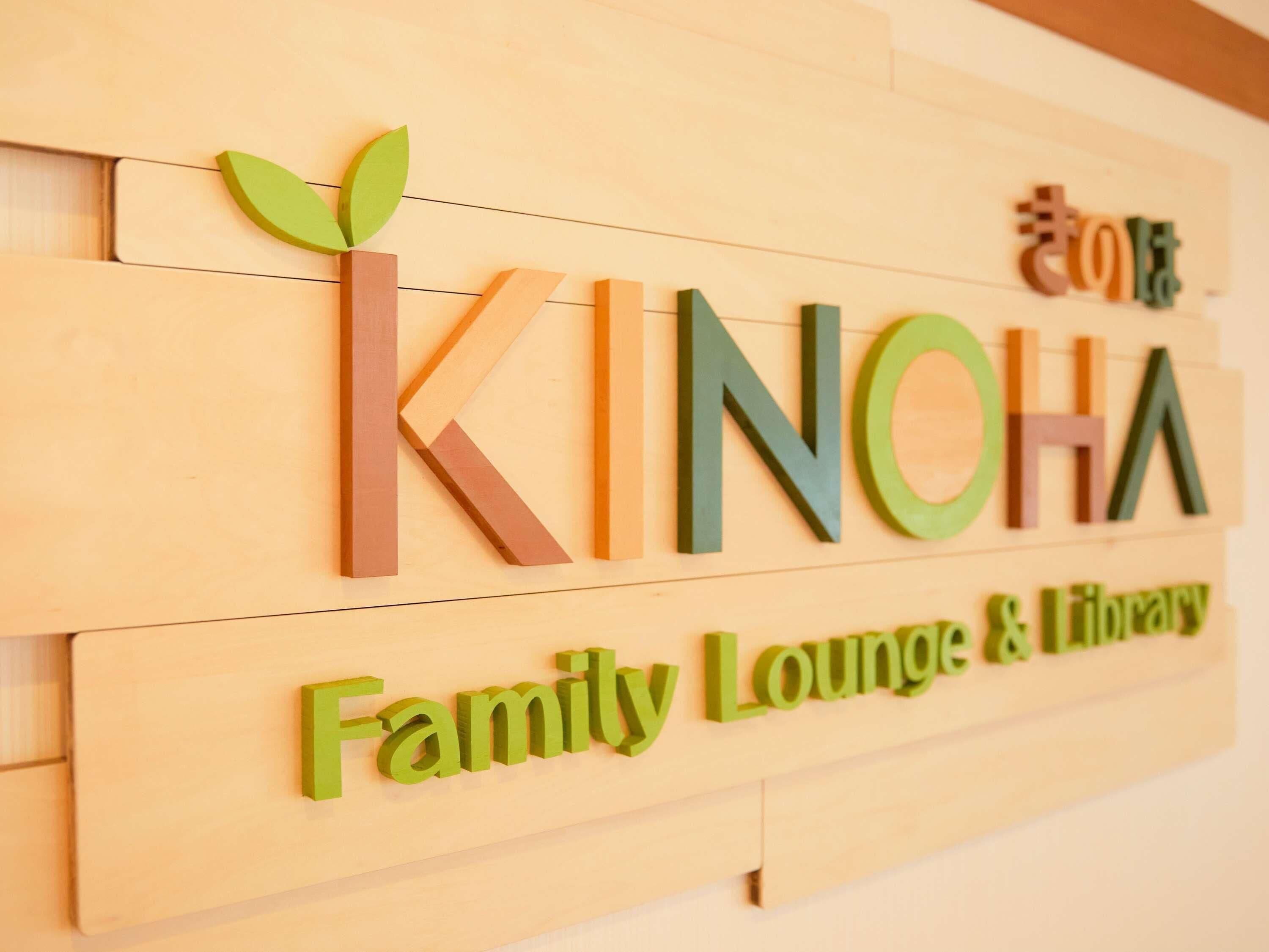 Uma placa de madeira com as palavras "KINOHARA" e "Family Lounge & Library" em letras coloridas.
