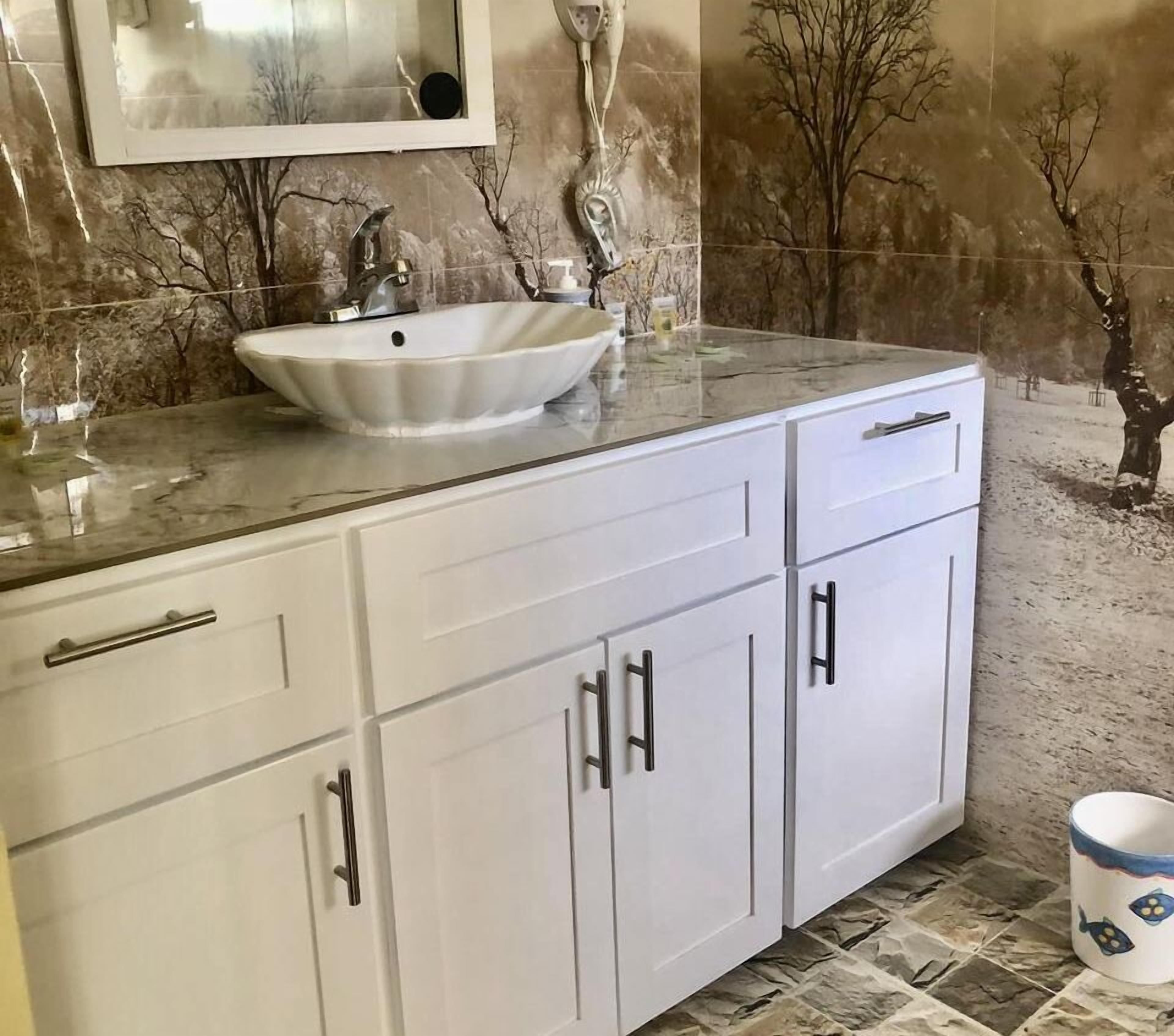 A bathroom with a white vanity, a vessel sink, and a marble countertop.