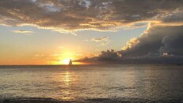 A beach scene with a sunset over the ocean. - Sunset Oasis (Derricks)
