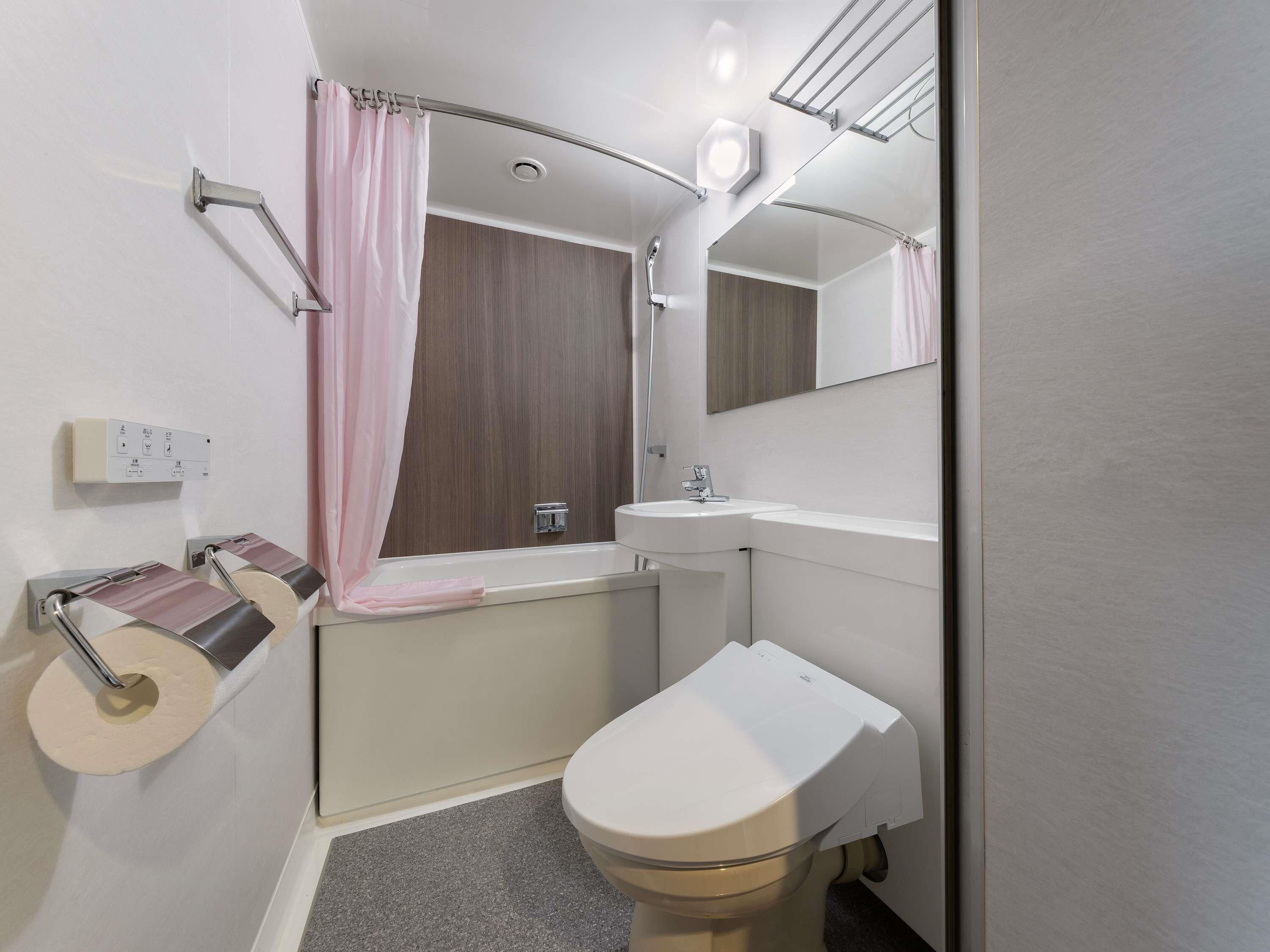 Un baño con inodoro, lavamanos y cortina de ducha.
