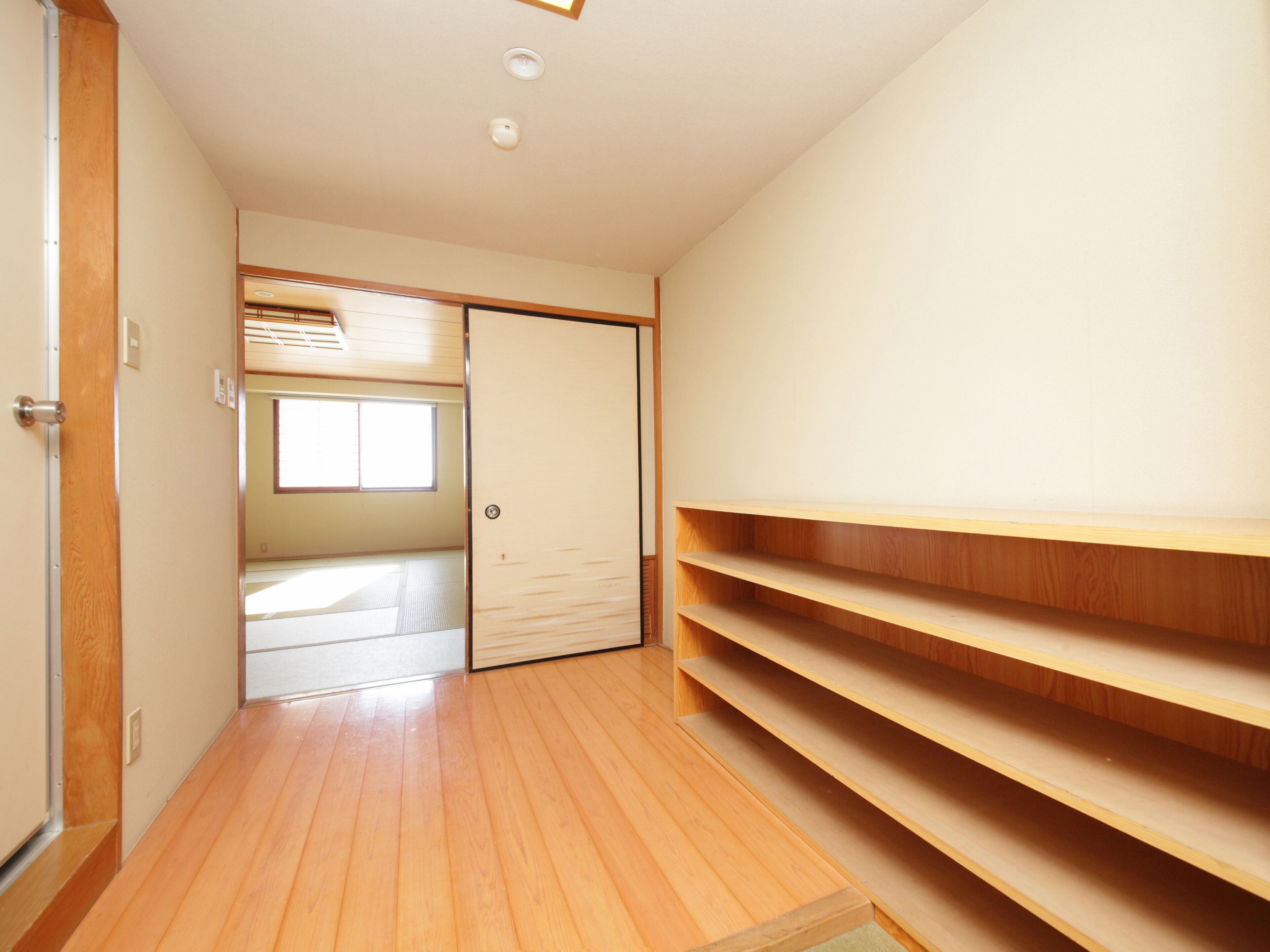A hallway with wooden flooring, a sliding door, and built-in wooden shelves.