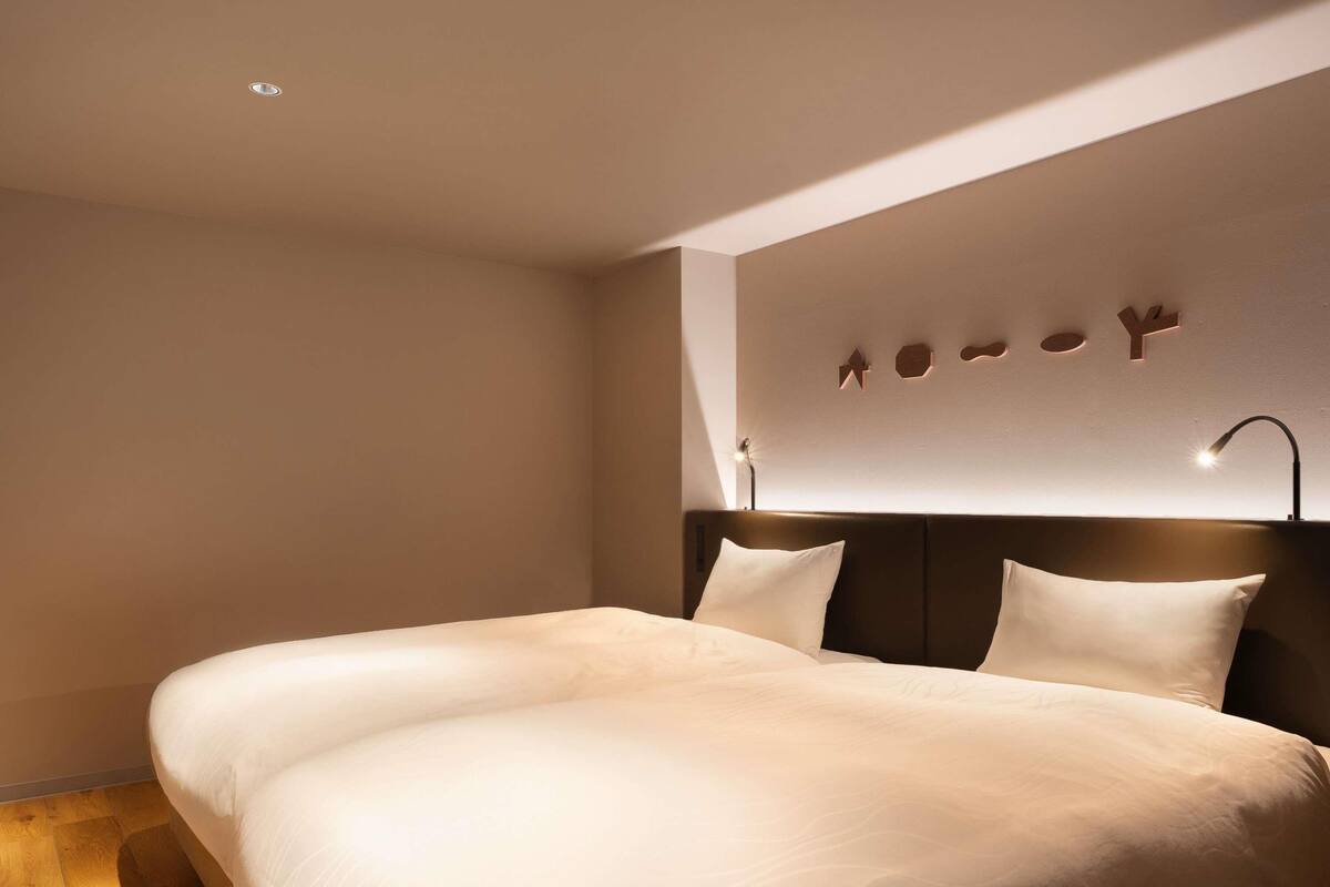 Una habitación de hotel moderna con una cama grande, un cabecero con iluminación integrada y una lámpara de pared.