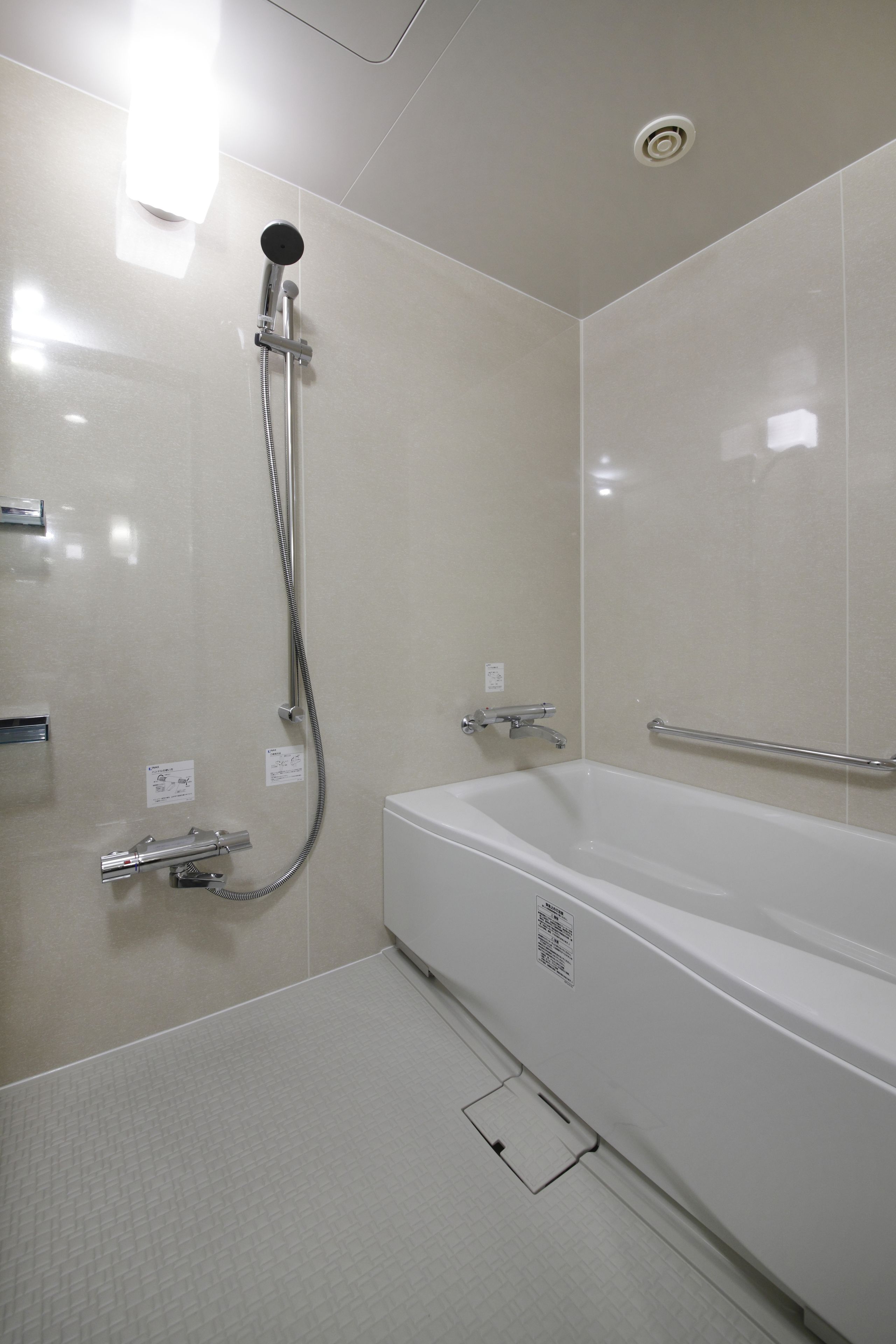 A modern bathroom with a shower, a bathtub, and a handrail.