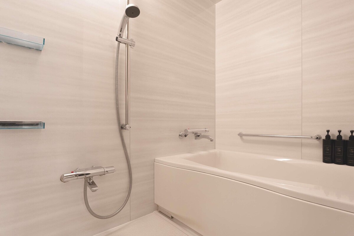 Un baño moderno con bañera, ducha y barras de apoyo.