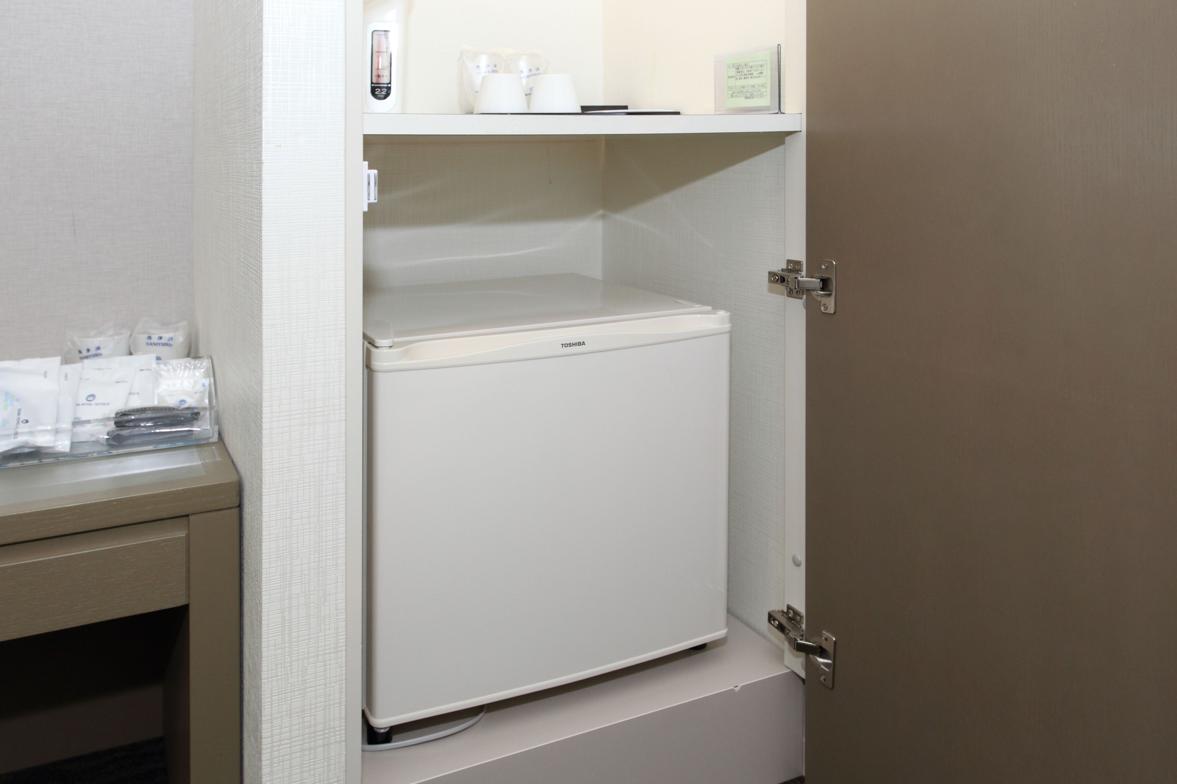 A white refrigerator in a kitchen with a beige countertop and cabinets.