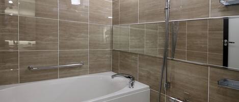 Un baño moderno con una bañera independiente, un cabezal de ducha manual y un perchero de pared.