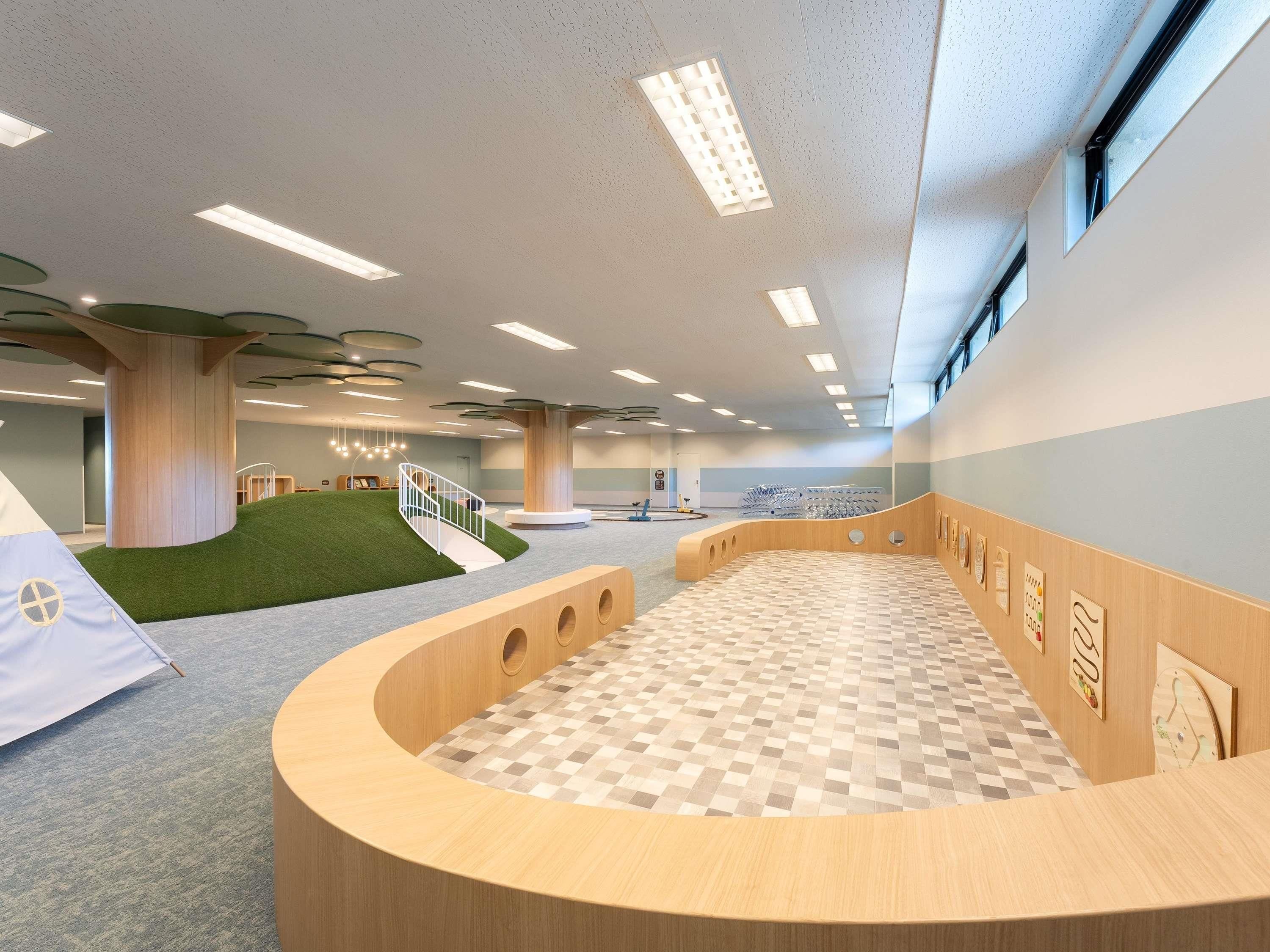 A modern interior with a central wooden structure, a checkered floor, and a staircase leading to a green area.