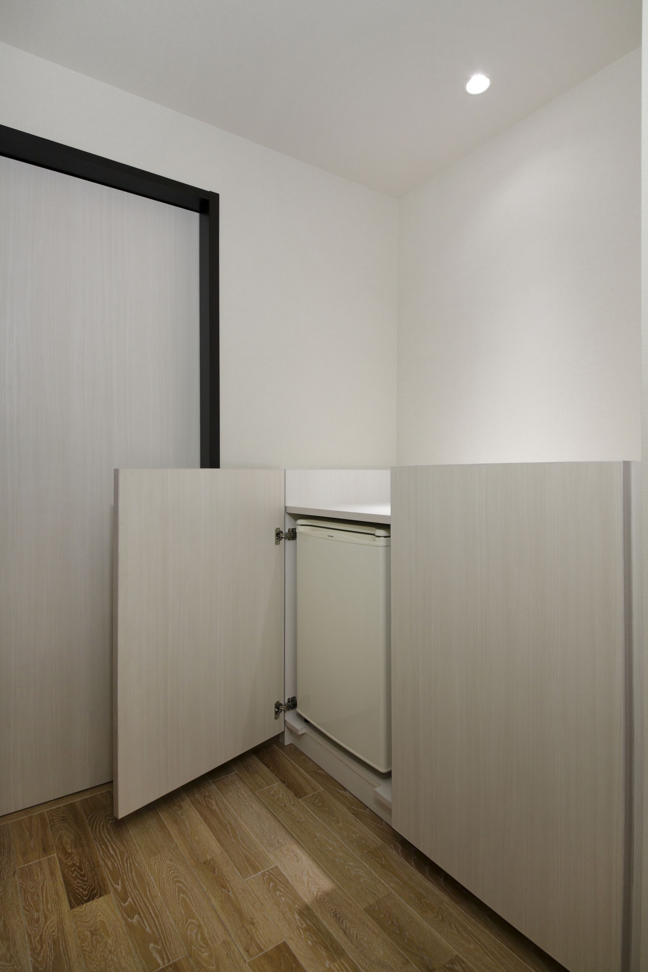 A room with a wooden floor, white walls, and a partially open door.