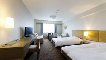A hotel room with two beds, a desk with a computer, a chair, a TV, and a lamp.