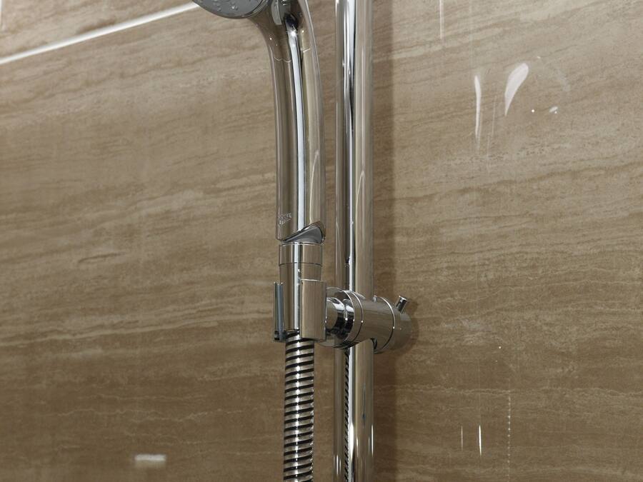 A chrome showerhead with a flexible hose attached to a wall-mounted faucet.