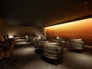 A dimly lit room with a warm wall and several wicker chairs arranged around a central table. - Grand Mercure Minamiboso Resort & Spa (Minamiboso)