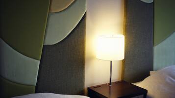 Een net opgemaakt bed met witte lakens, een klein nachtkastje met een lamp en een hoofdbord met een structuur.