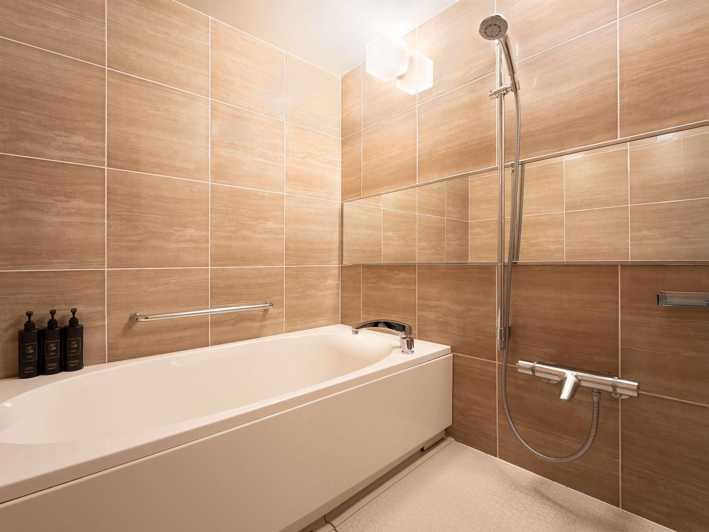 A modern bathroom with a bathtub, a handheld showerhead, and a towel rack.