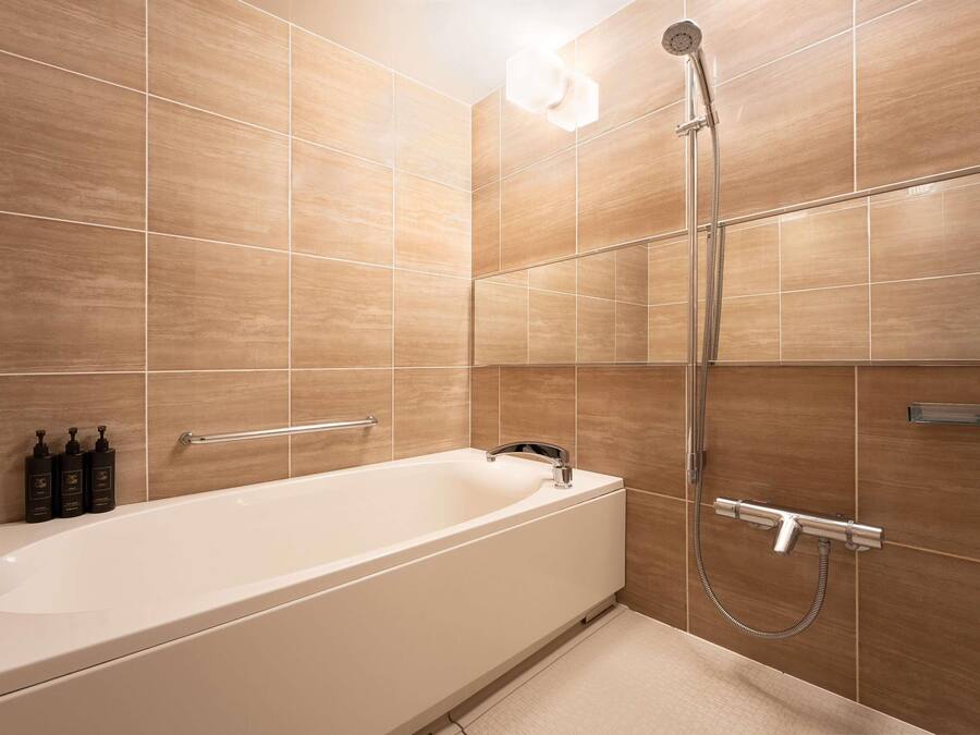 A modern bathroom with a bathtub, a handheld showerhead, and a towel rack.