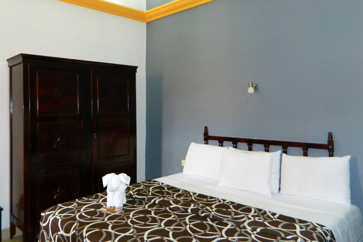 A bedroom with a bed, a wardrobe, and a wall-mounted light fixture.