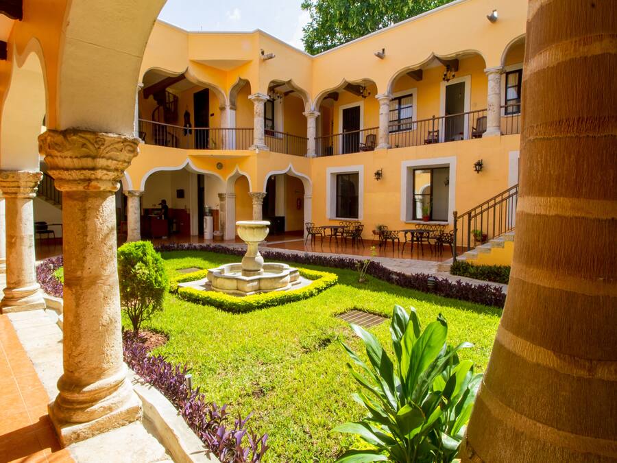 A courtyard with a fountain, columns, and a well-maintained garden.