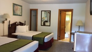 A hotel room with two beds, a refrigerator, a lamp, and a painting on the wall. - Adirondack Oasis Motel (Lake George)