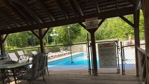 A covered pool area with a lifeguard warning sign, lounge chairs, and a wooden deck. - Adirondack Oasis Motel (Lake George)