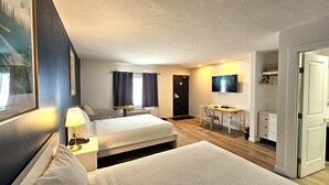 A hotel room with two beds, a desk, a chair, a TV, and a door. - Cloud 9 Inn (Whitecourt)