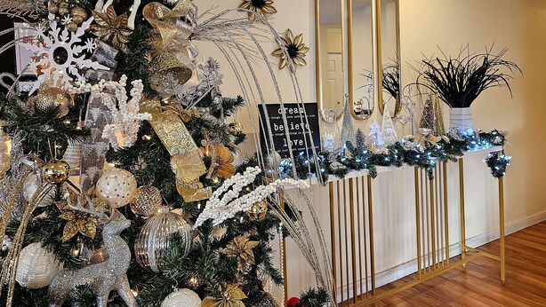 A Christmas tree with gold and white decorations, a mirror, and a sign with a quote. - Cloud 9 Inn (Whitecourt)