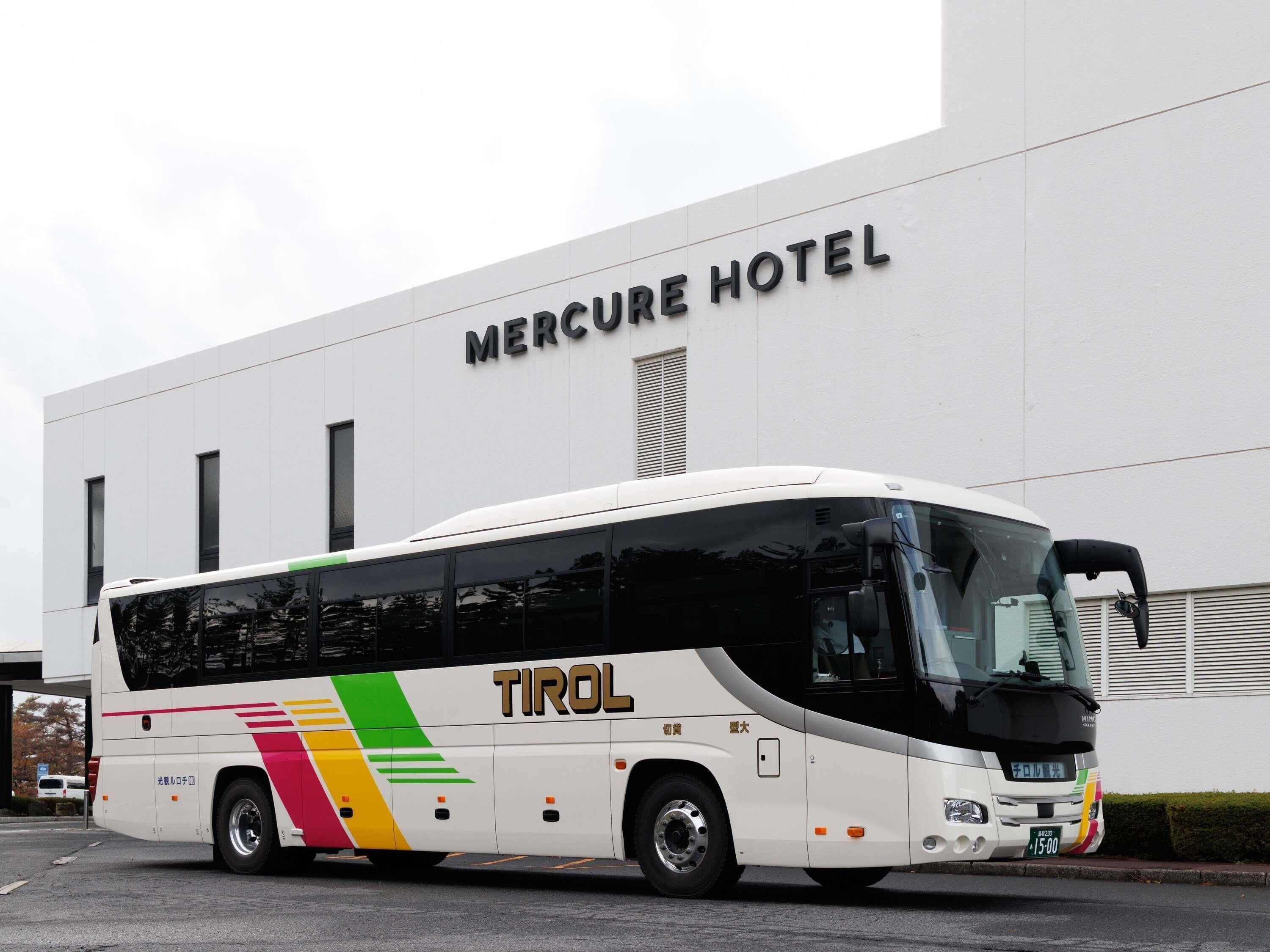 A white bus with 'TIROL' and 'MERCURE HOTEL' signage parked in front of a building.