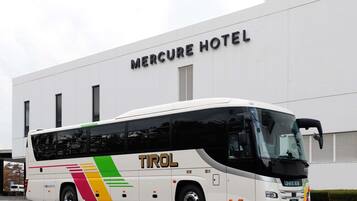 A white bus with 'TIROL' and 'MERCURE HOTEL' signage parked in front of a building.