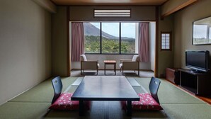 Une pièce avec un plafond en bois, une table entourée de chaises, un téléviseur et une vue sur une montagne, visible à travers de grandes fenêtres.