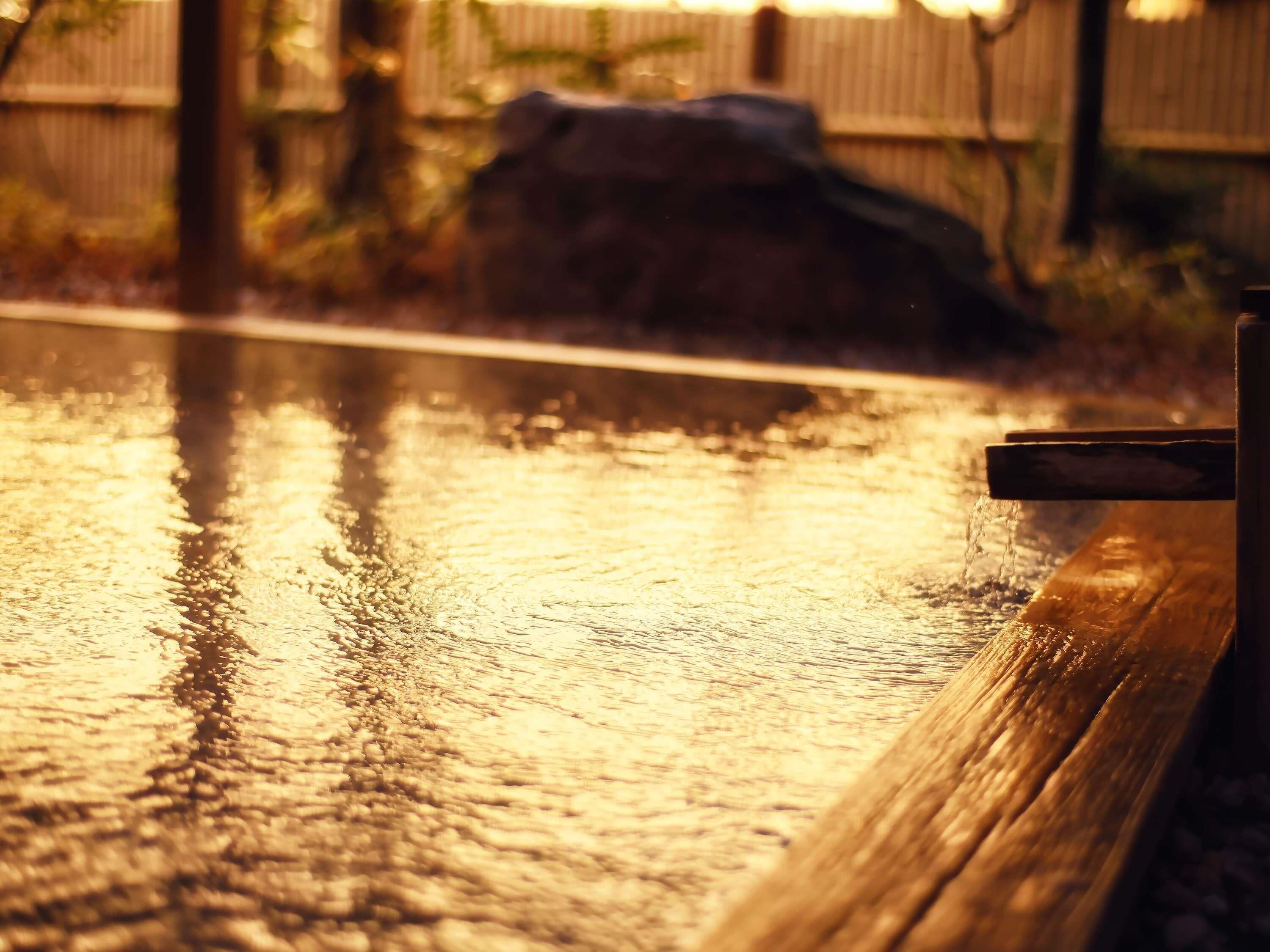A wooden bench by a wet surface reflecting light.