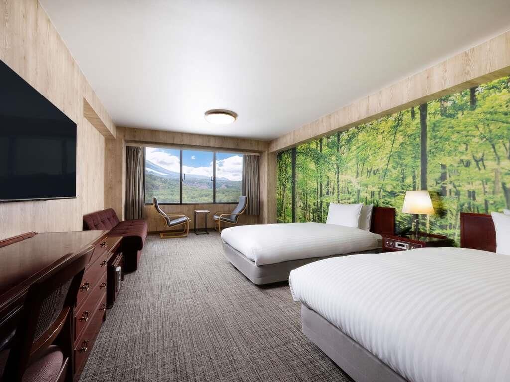 A hotel room with a large window, a bed, a desk, and a chair.
